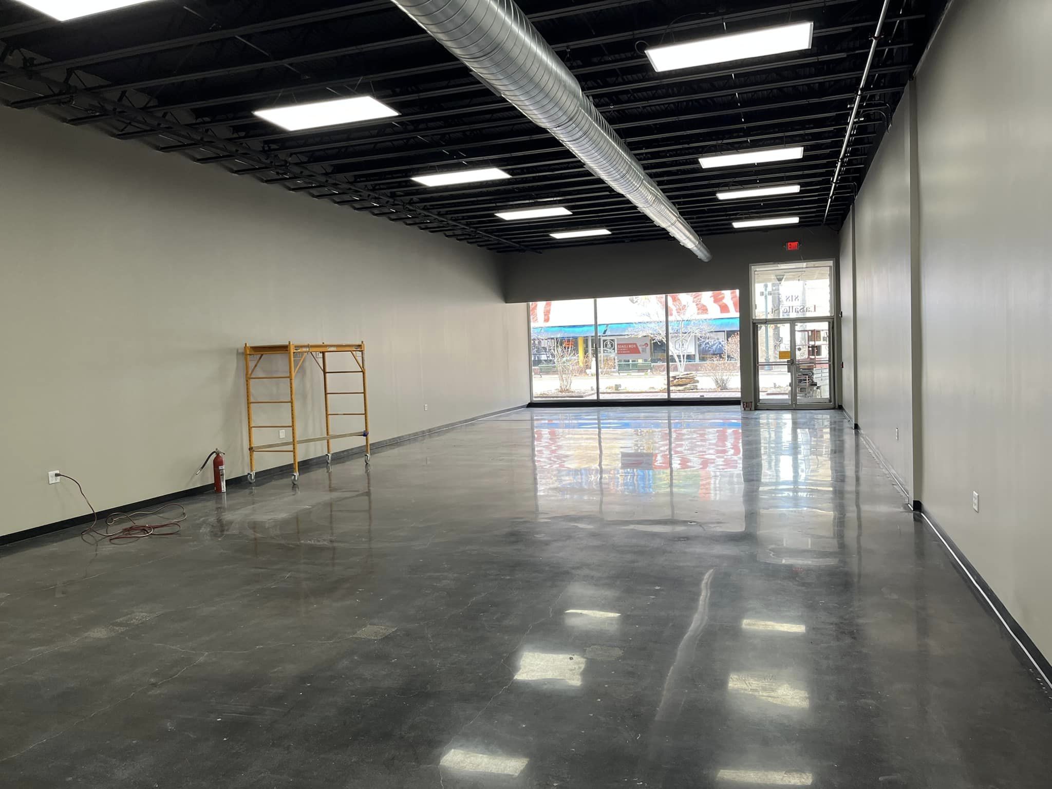 Empty space with concrete floors and white walls looking to the street
