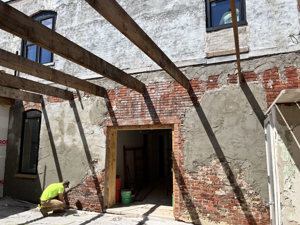 Exposed brick wall with wet antiqued plaster