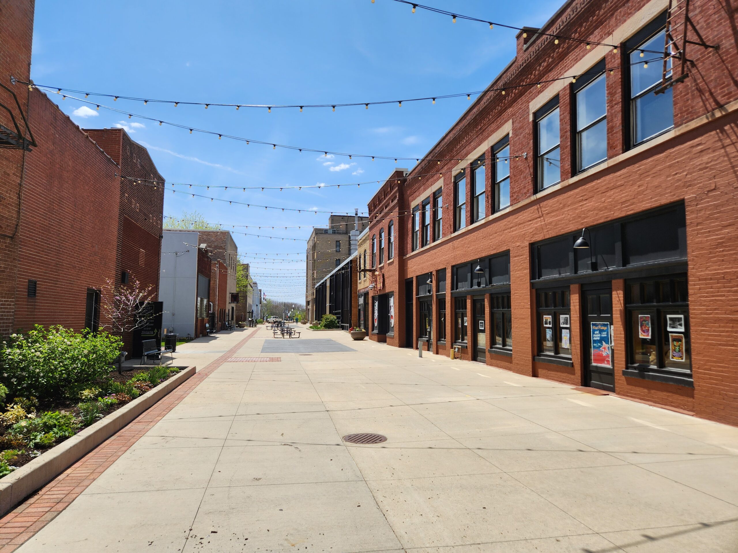 43 Galena as a plain brick building on the plaza with bistro lights above. The view is down the plaza, a walkable pedestrian area.