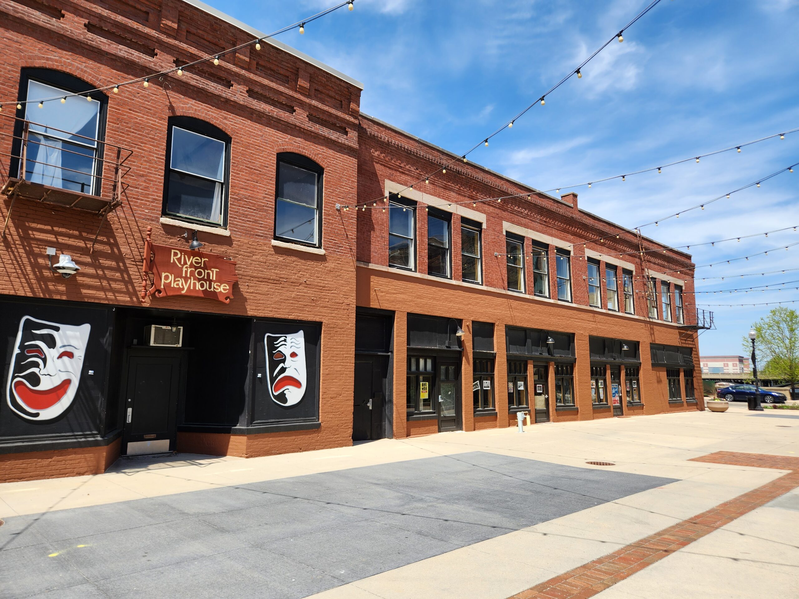 43 Galena as a plain brick building on the plaza with bistro lights above. Next door to the building is a theatre.