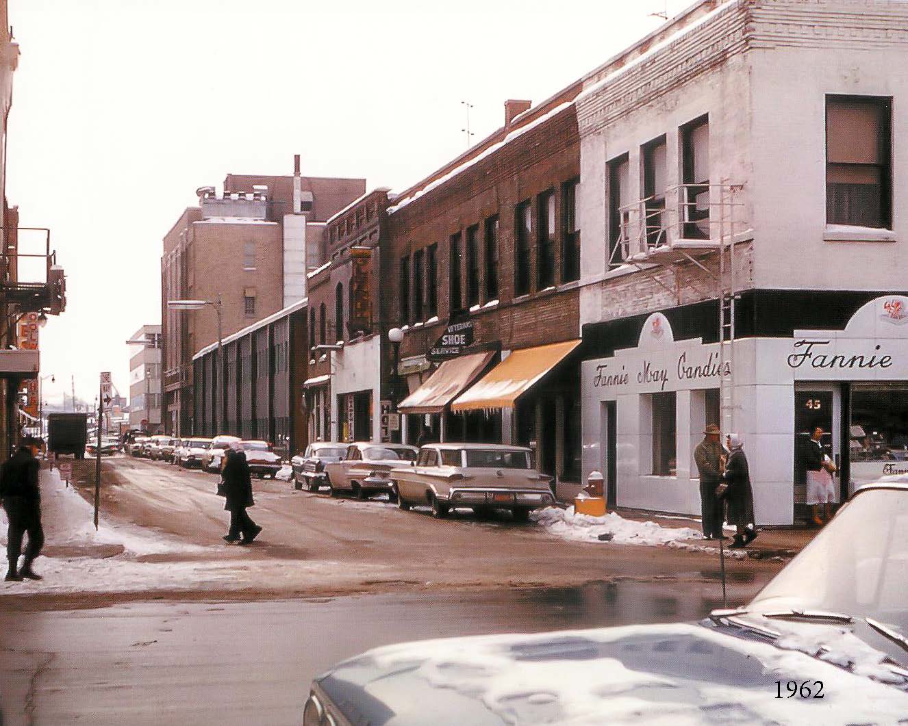 A photo from 1962 depicting a city street. 43 Galena is a Fannie May Candies company store.