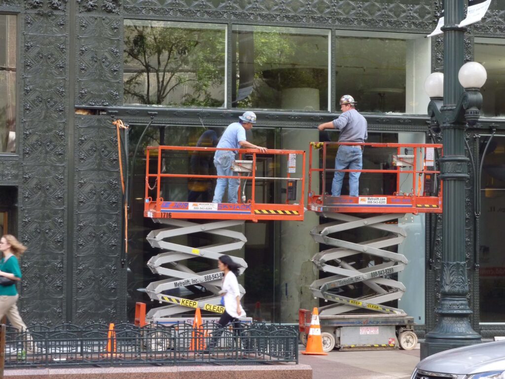 Workers restoring cast iron ornaments on the Sullivan Center on State Street, Chicago, IL.